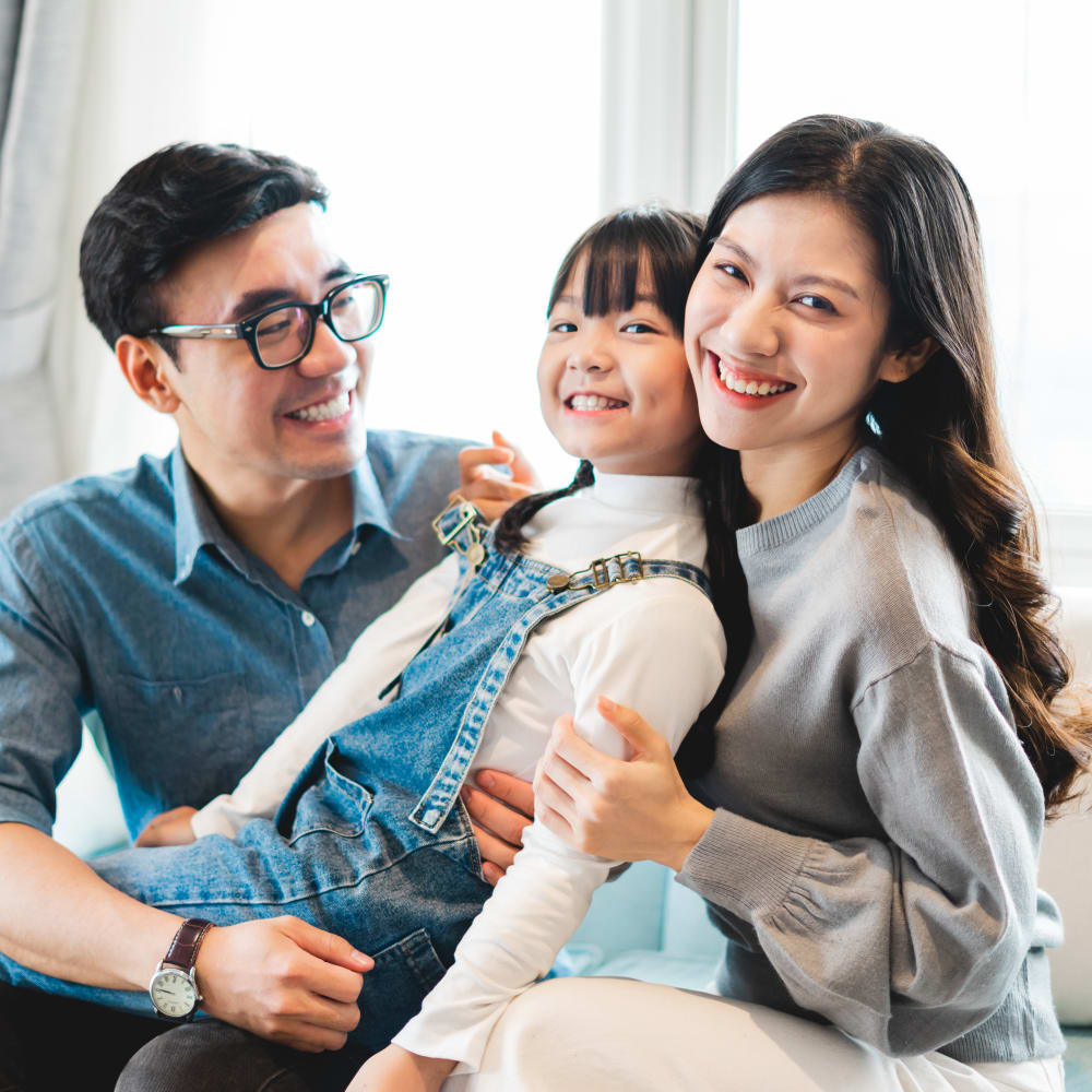 A young girl is sitting between her parents smiling.