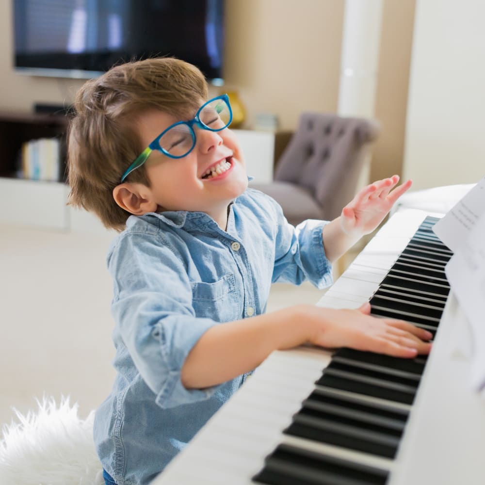 A young boy is smiling and playing the piano.