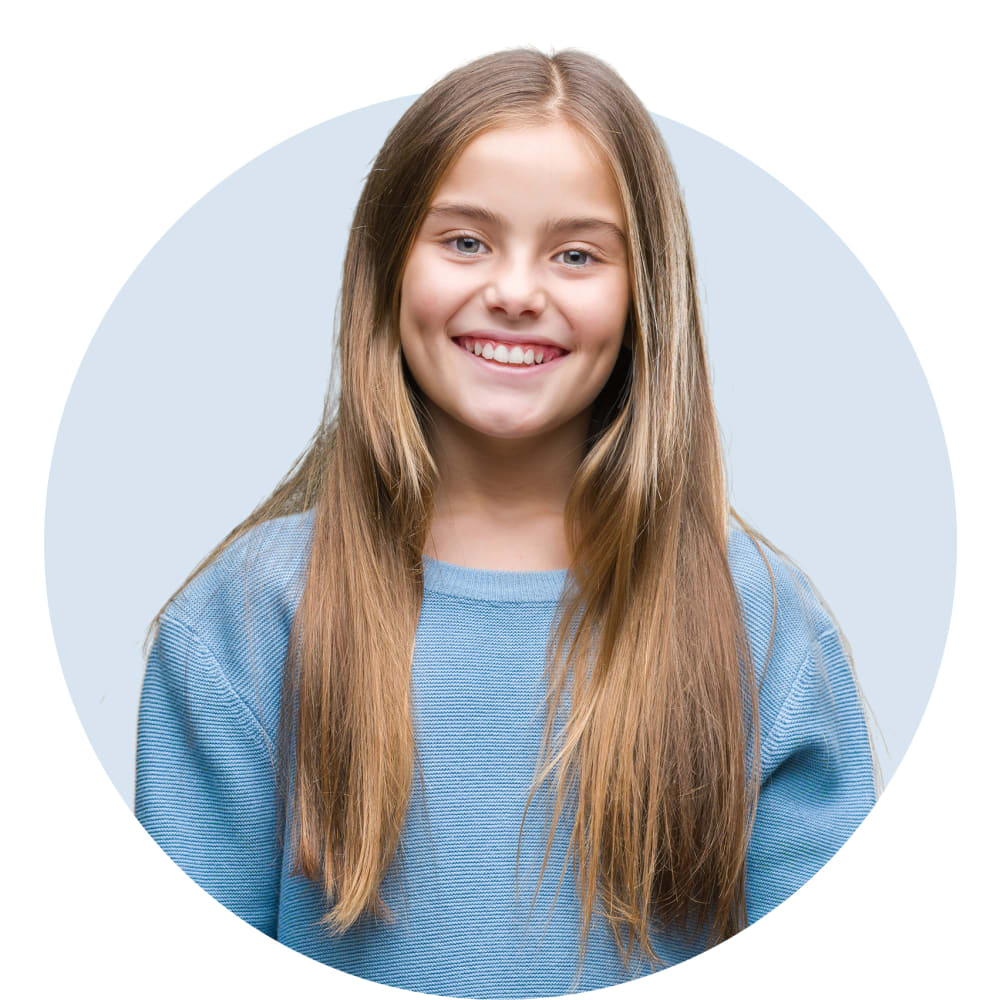 A young girl in a blue sweater is smiling