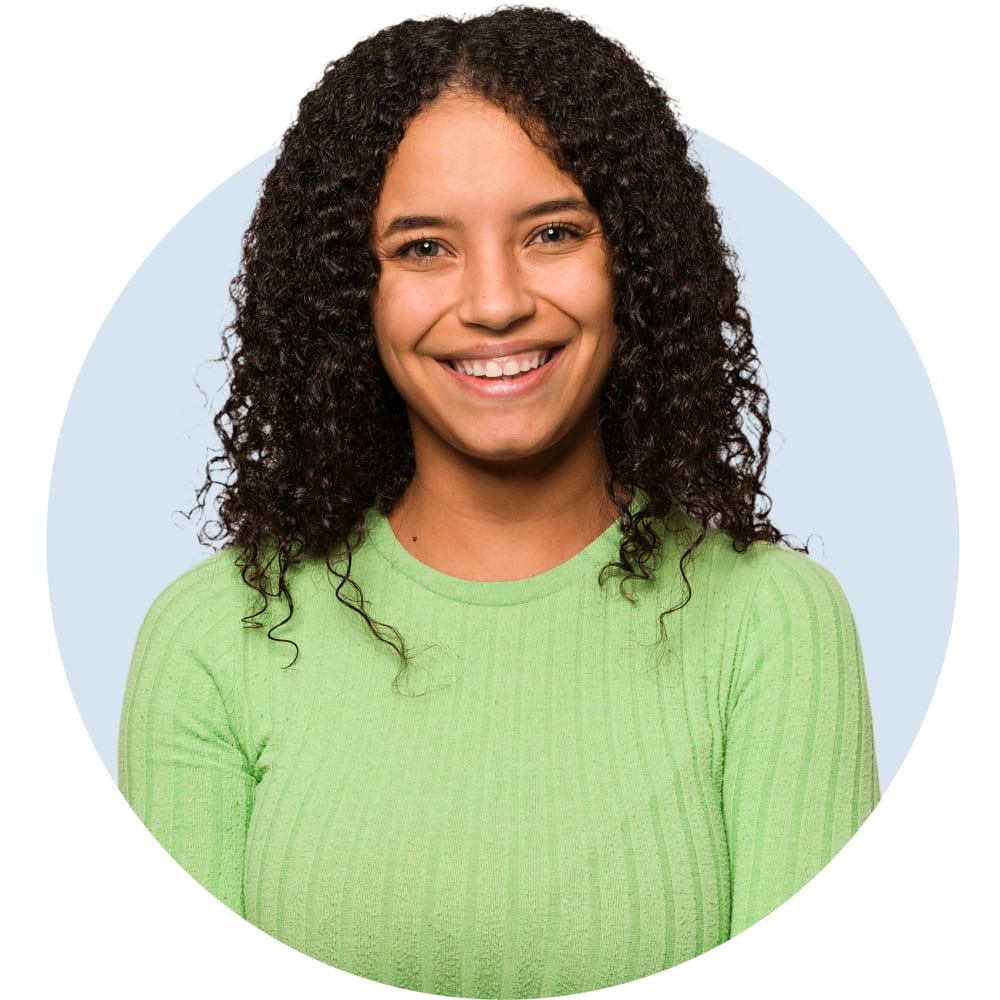 A girl in a green sweater is smiling.