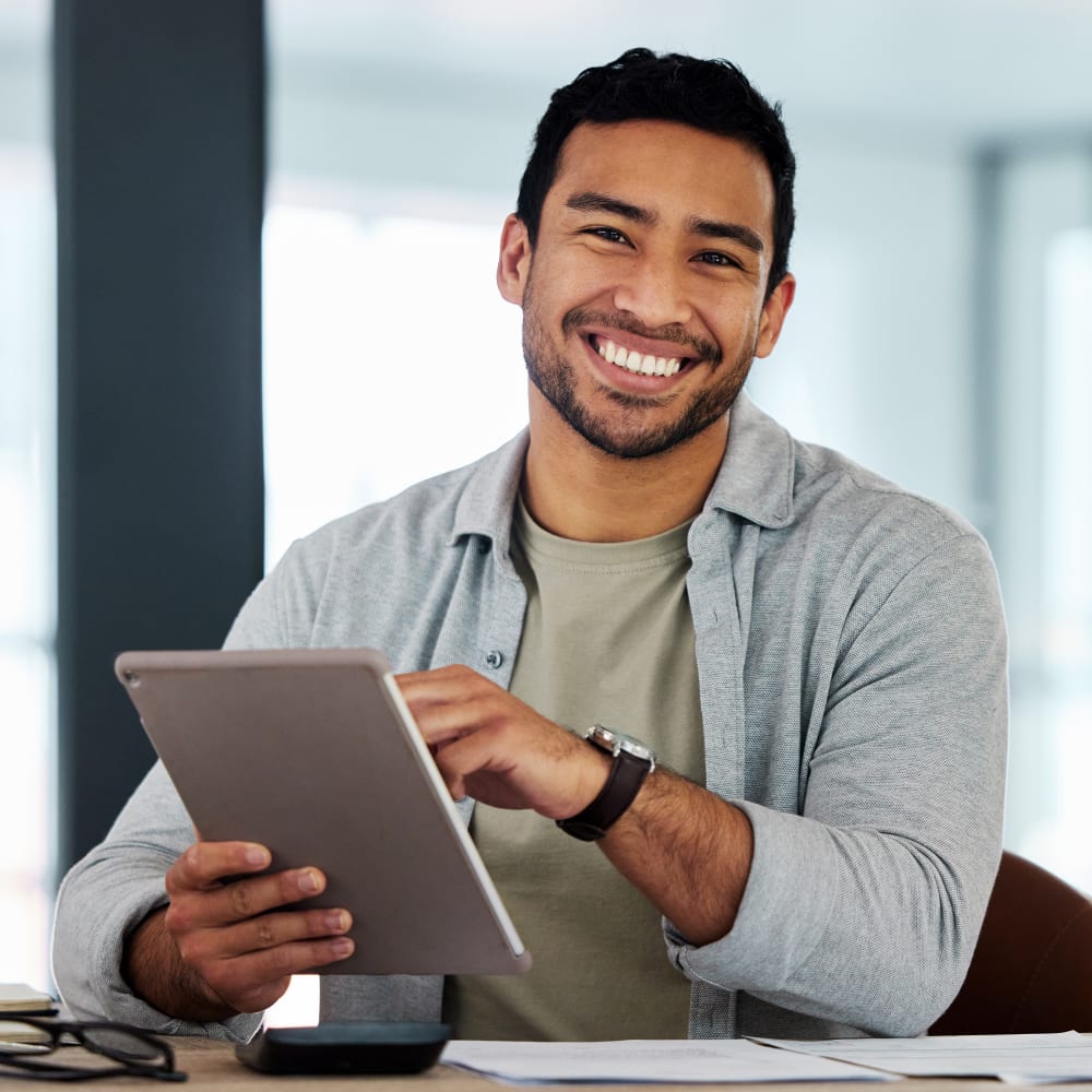 A man using a tablet is smiling.