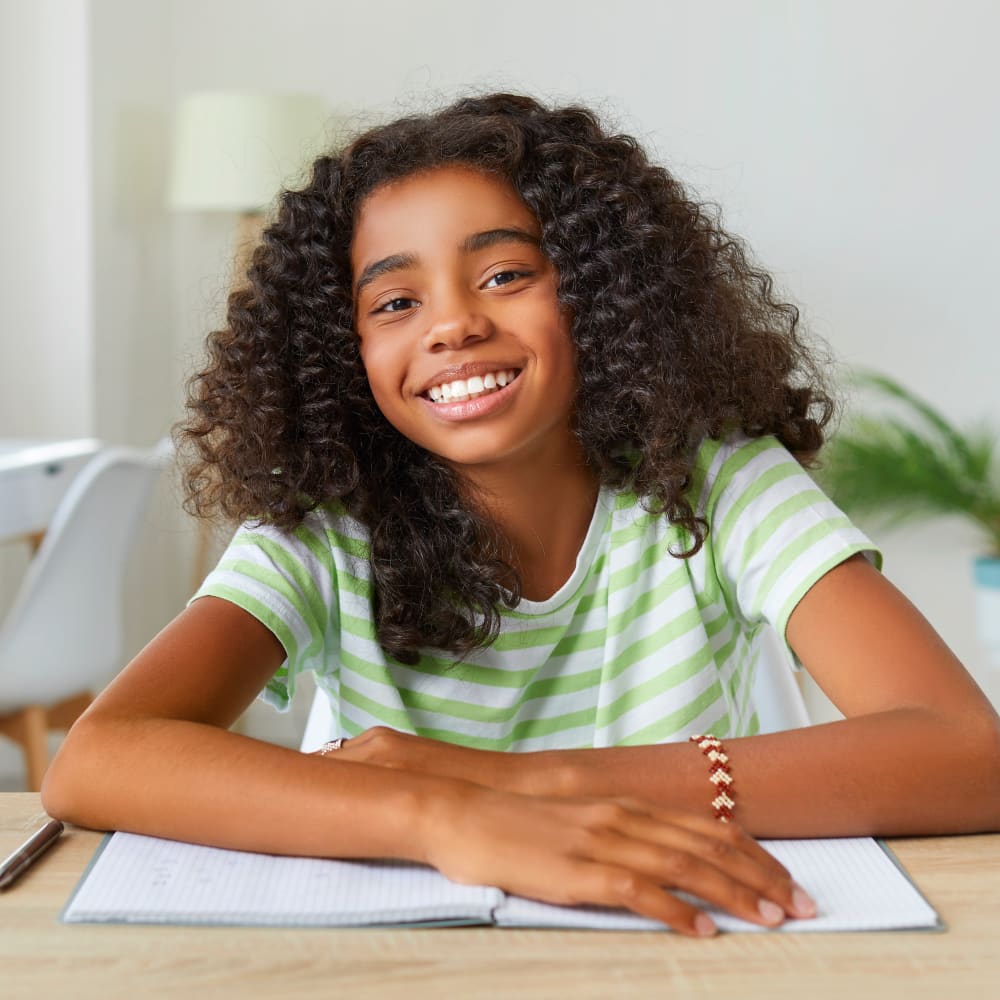 A young girl with bright white teeth is smiling.