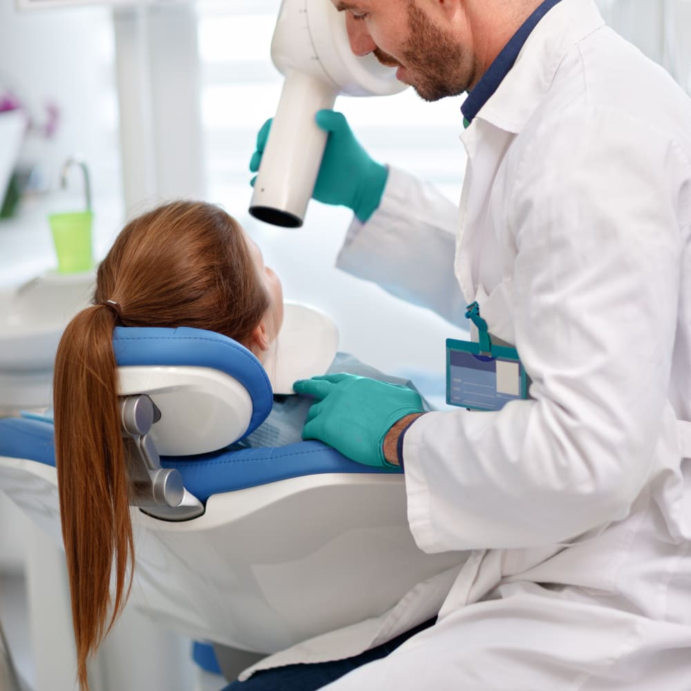 A dental professional prepares a patient for a dental x-ray.