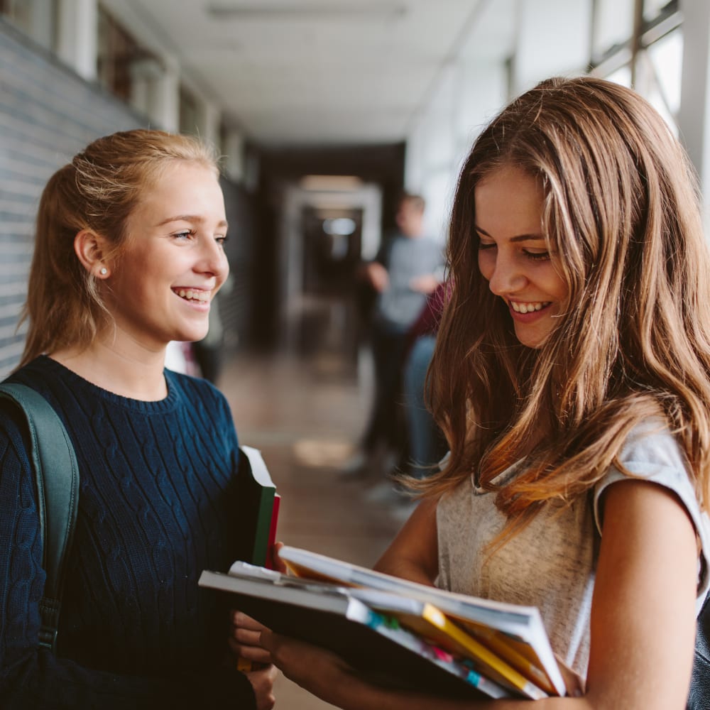 Two girls are in a school hallway.